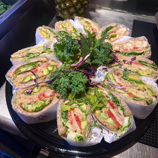 A platter of Tribal Cafe wraps, filled with chicken, avocado, tomatoes, and lettuce, garnished with kale.