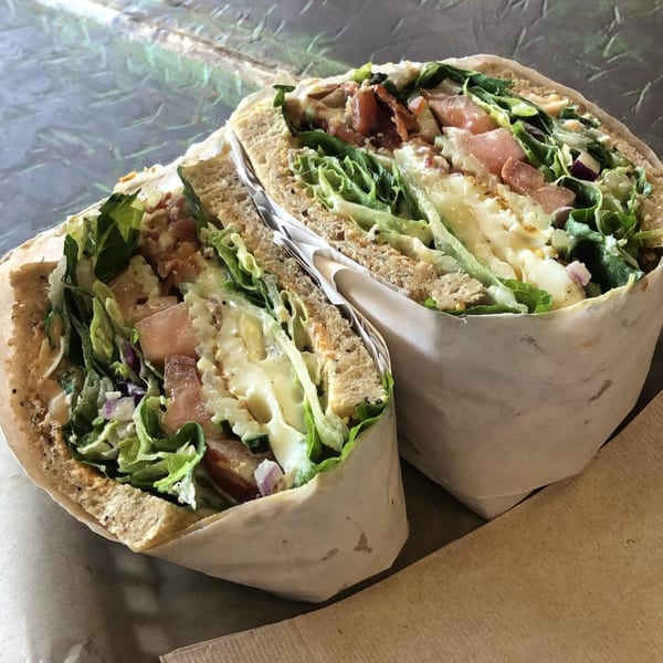 A large, halved sandwich from Tribal Cafe, filled with lettuce, tomatoes, and creamy dressing.